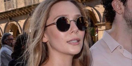Gold slim round sunglasses with dark lenses worn by a person