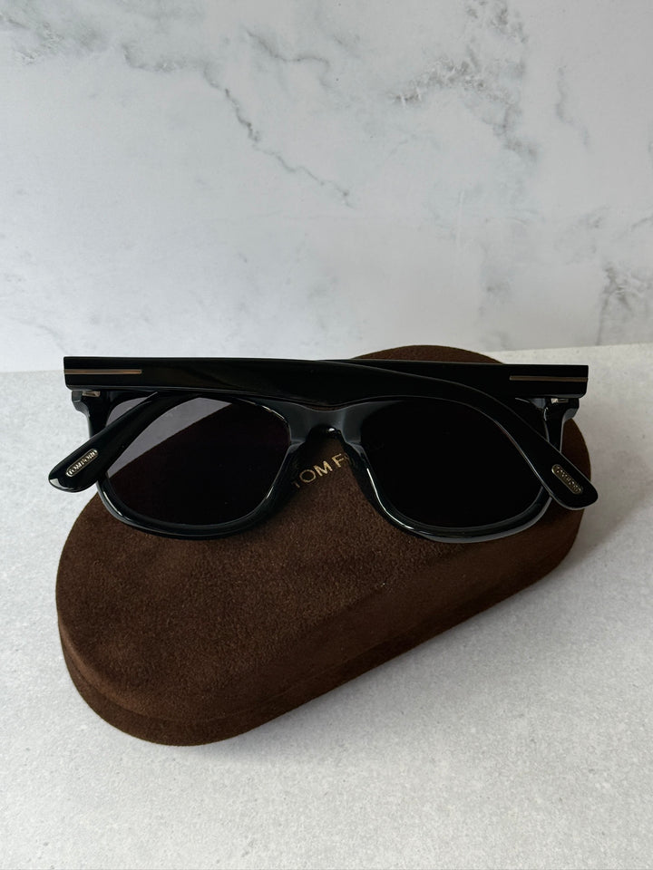Black round-edge sunglasses with dark polarized lenses and temple logo