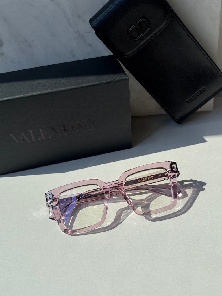 Pink square eyeglasses with clear lenses and V-shaped metal logo hinge detail