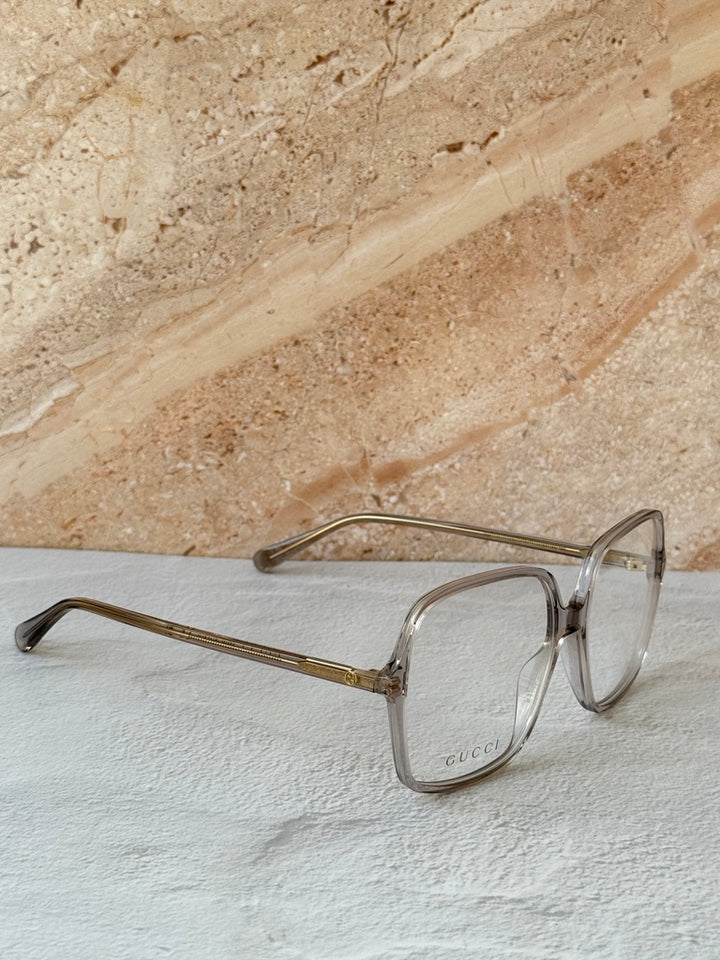 Gucci transparent grey eyeglass frames with gold-tone bridge and temples