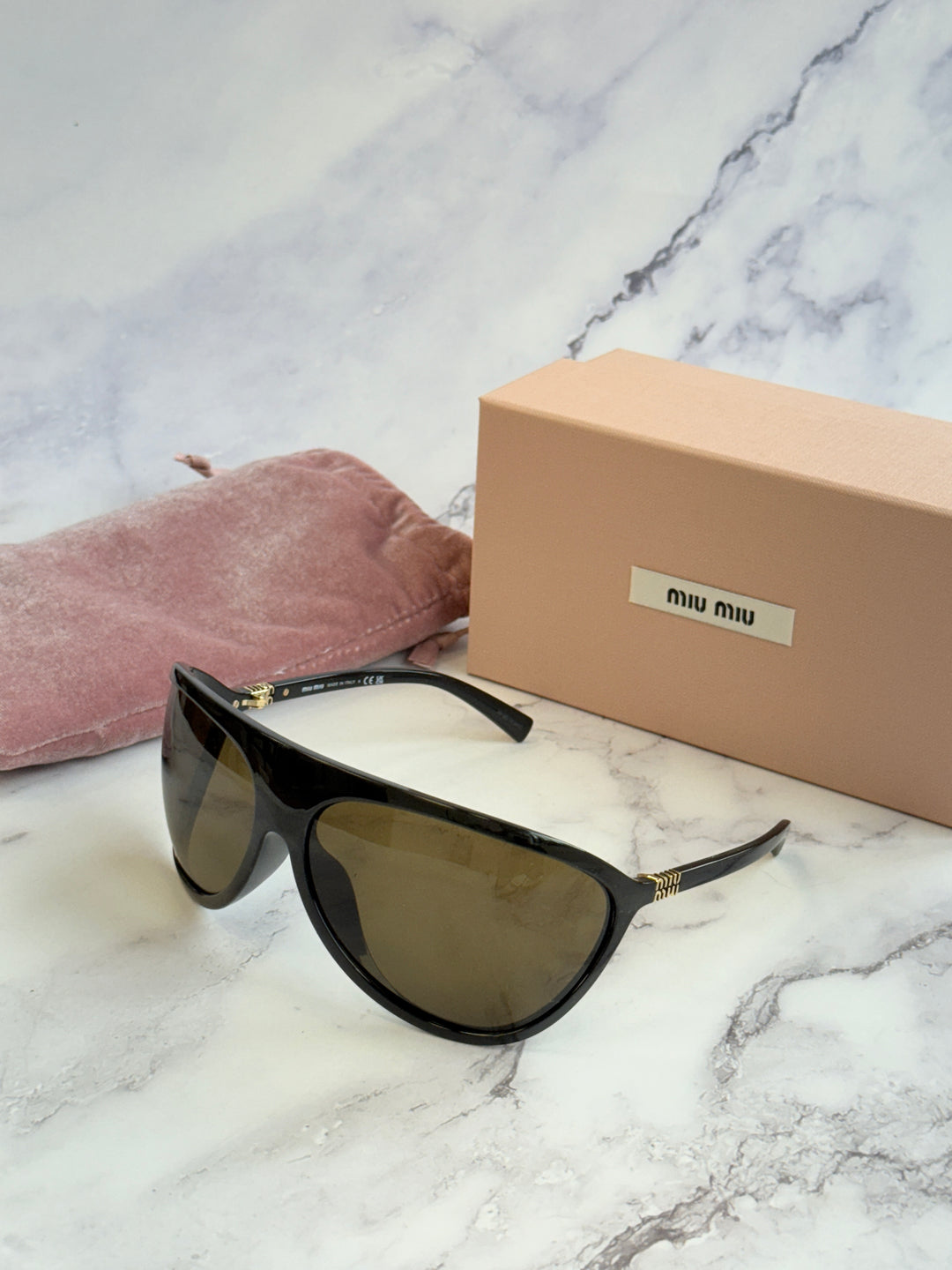 Black shield sunglasses with brown lenses and gold-tone accents on the temples.