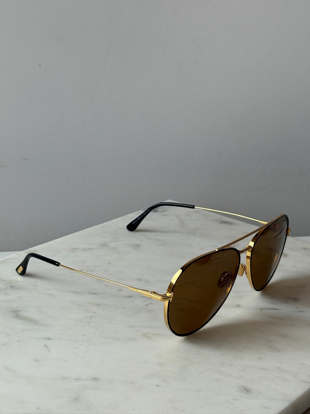 Gold-tone aviator sunglasses with brown lenses, angled side view