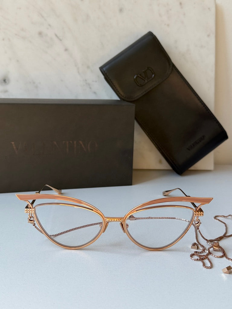 Cat-eye eyeglass frames with gold-tone metal and beige lenses with chain accents