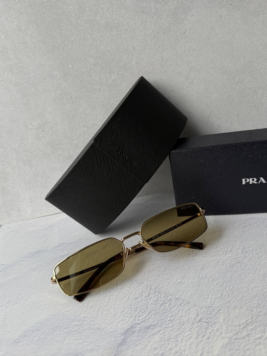 Gold metal rectangular sunglasses with brown-tinted lenses, with black protective case.