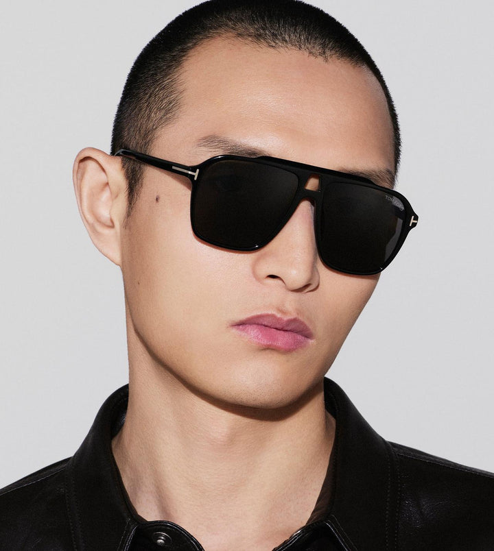 Black sunglasses with dark lenses and thick temples, worn on a model.