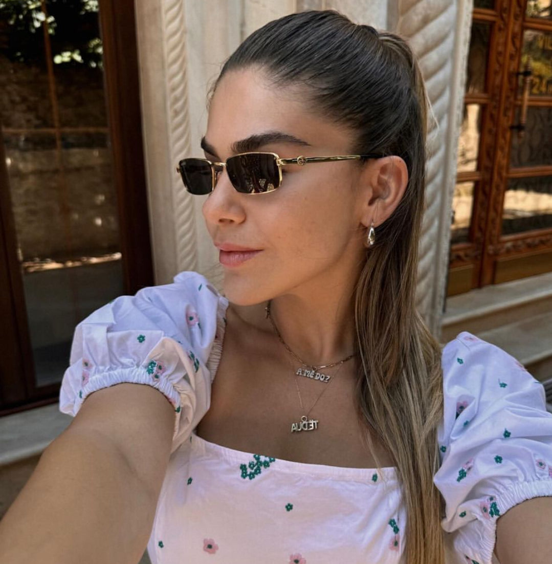Gucci rectangular sunglasses on model, gold frame with dark lenses