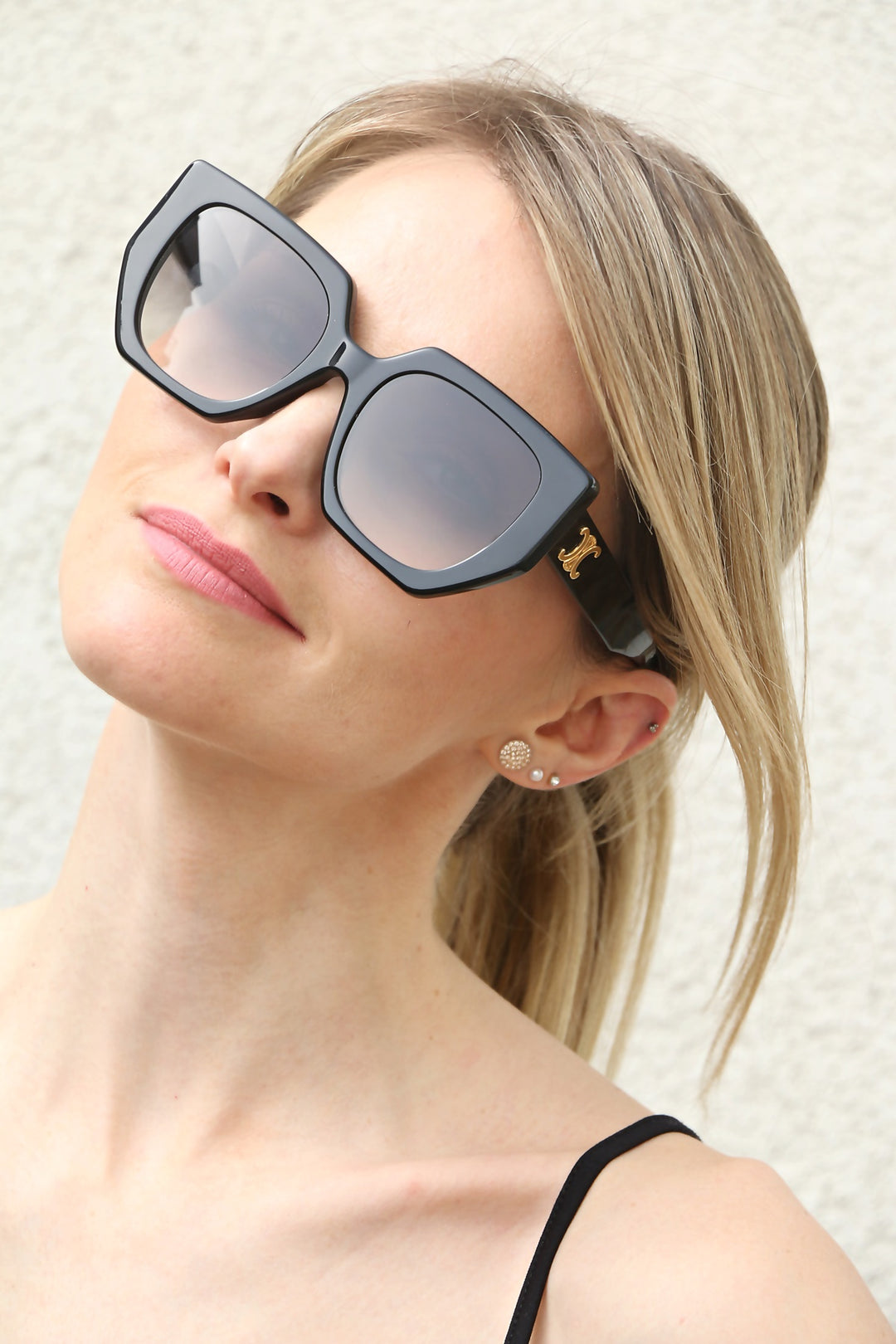 Celine black squared cat-eye sunglasses on model, gold temple logo detail