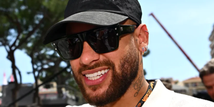 Man wearing black square sunglasses with gold-tone details and dark lenses