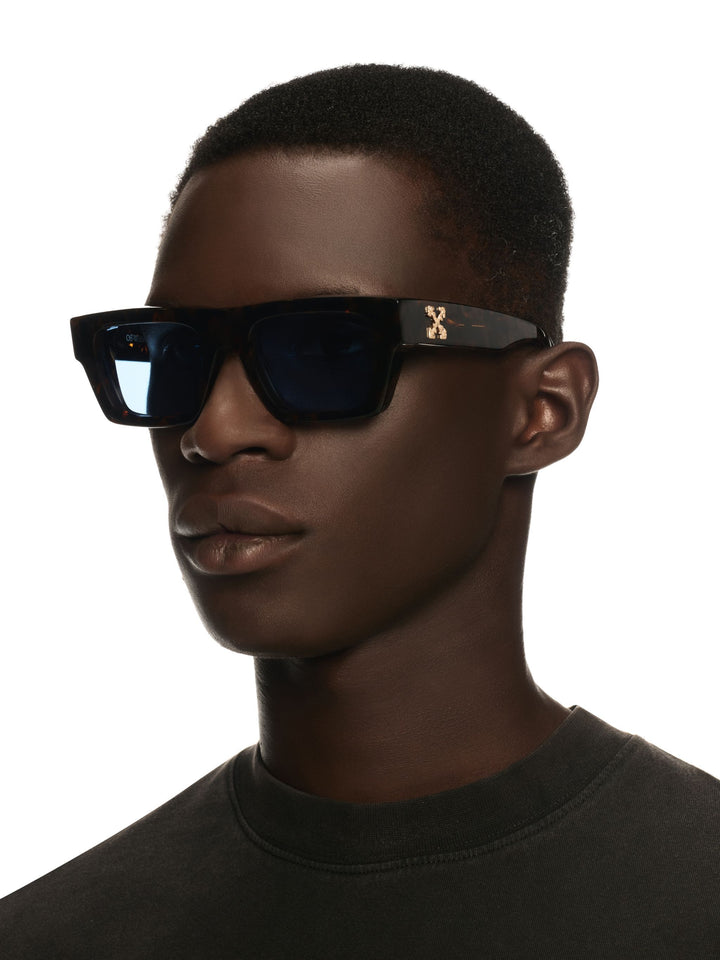Black sunglasses on a person with dark lenses and Off-White logo at the temple
