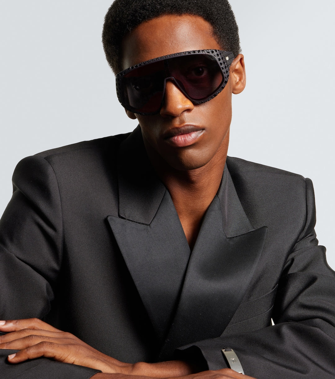 Man wearing Dior black wrap sunglasses with perforated frame and dark tinted lenses