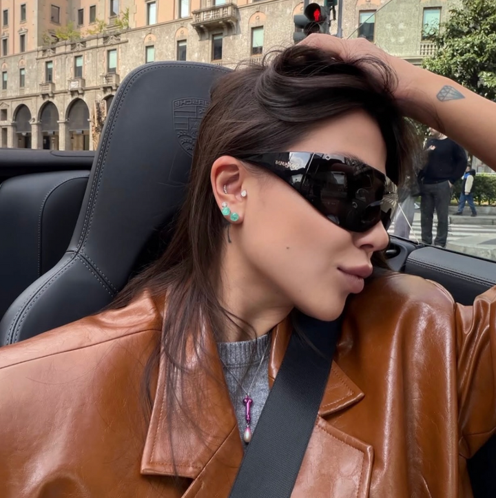 Black wrap mask sunglasses worn by model, dark lenses with Saint Laurent logo