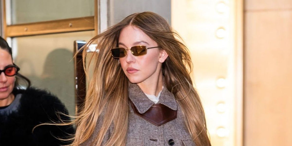 Prada sunglasses worn by model, gold frame with brown tinted lenses