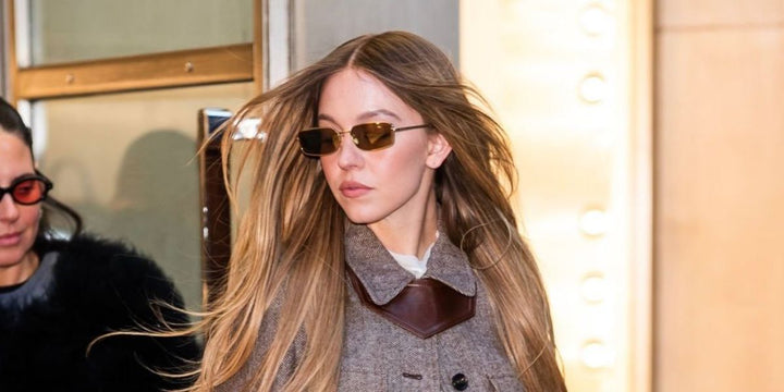 Prada sunglasses worn by model, gold frame with brown tinted lenses