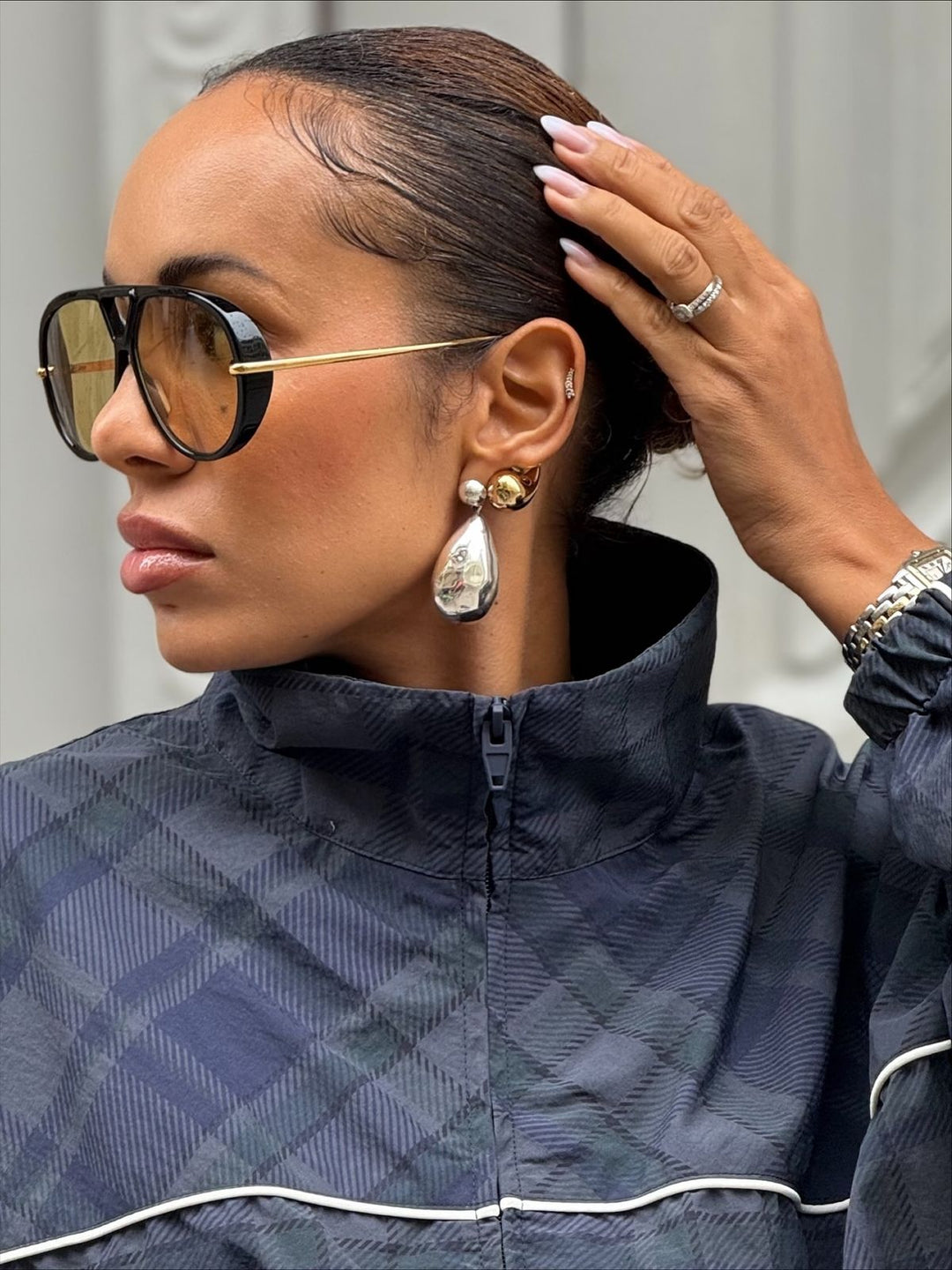 Aviator sunglasses with black frames and yellow lenses, paired with gold drop earrings.