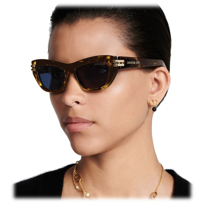 Havana brown Dior sunglasses on model with blue-tinted lenses and gold logo detailing