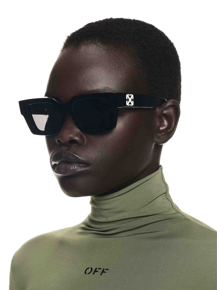 Black sunglasses with Off White logo across bridge, dark lenses on model