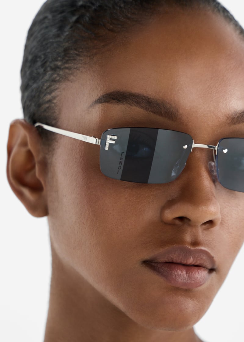 Fendi First rimless sunglasses on face, silver frame with dark blue lenses