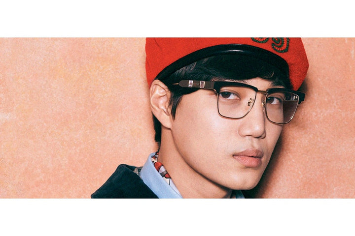 Square eyeglass frames on face, black front with gold-tone temple details.
