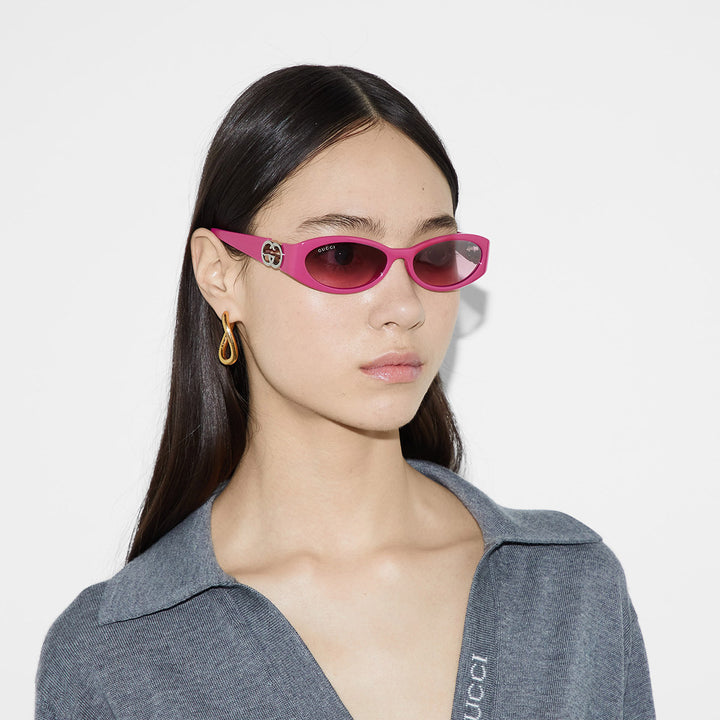 Gucci pink oval sunglasses on a model with dark tinted lenses