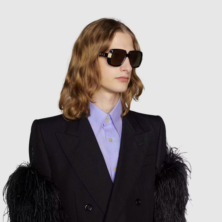 Gucci black square sunglasses on model with dark lenses and Gucci logo temple