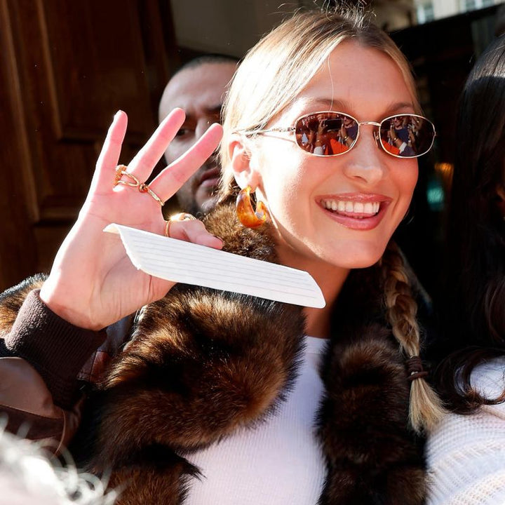 Gucci oval logo sunglasses on a smiling woman, dark brown lenses, gold-tone frame