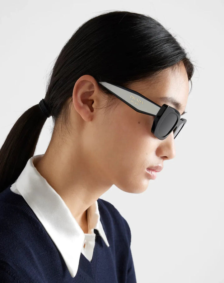 Prada black and white sunglasses with dark lenses, side profile.