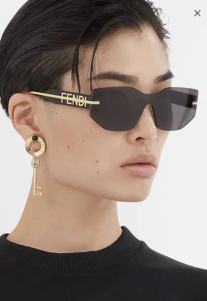 Fendi Fendigraphy black sunglasses on face, gold logo bar and dark lenses