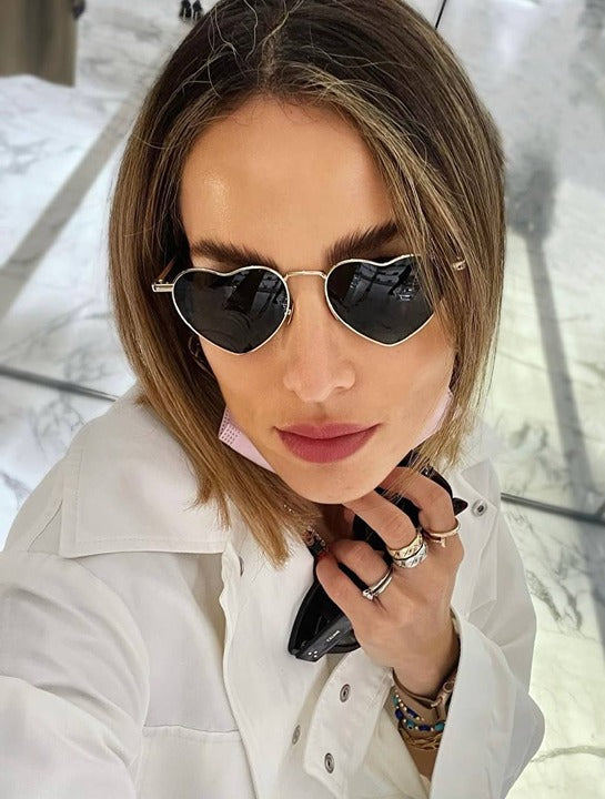 Heart-shaped sunglasses on model with gold-tone frames and dark tinted gradient lenses
