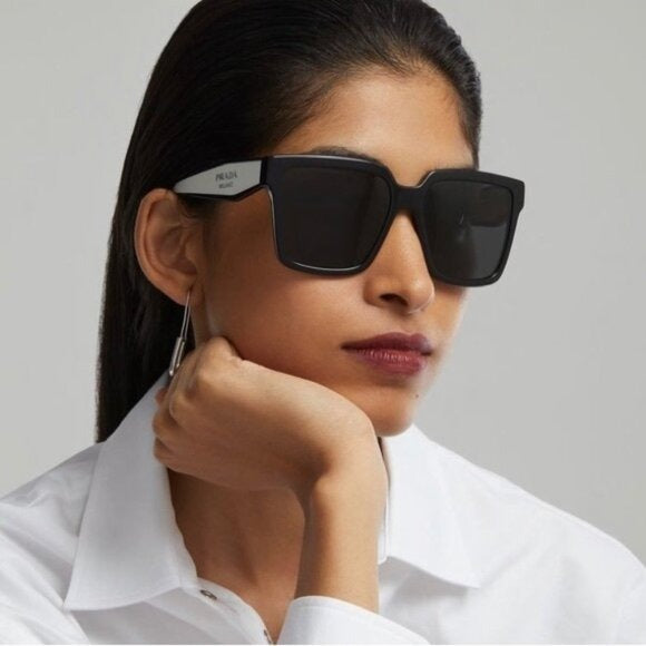 Prada oversized sunglasses with dark lenses, black frame and light trim at temples