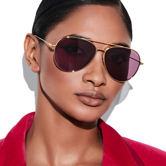 Gold-tone aviator sunglasses with dark purple lenses on model