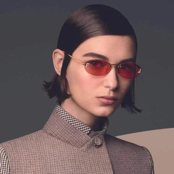Woman wearing gold thin-frame round sunglasses with red tinted lenses