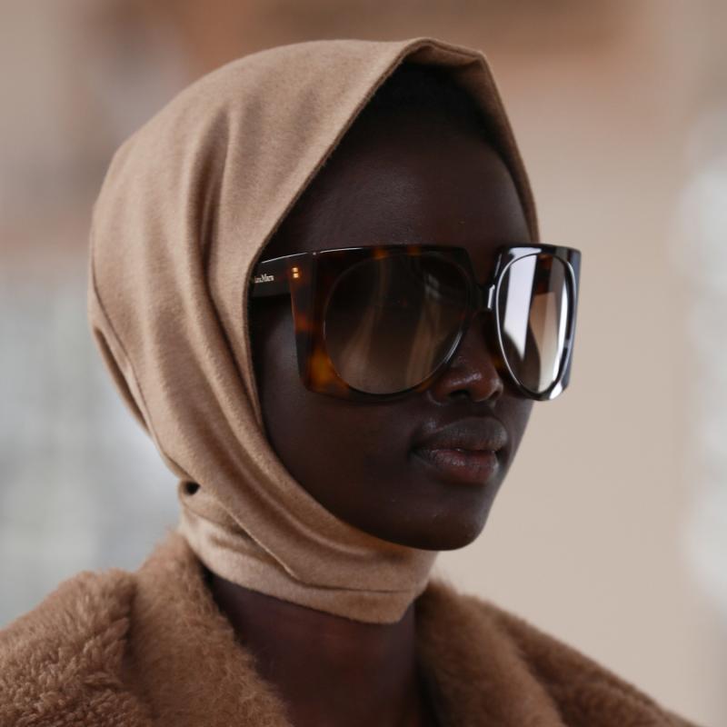 Oversized dark brown sunglasses with amber lenses on model wearing a hood
