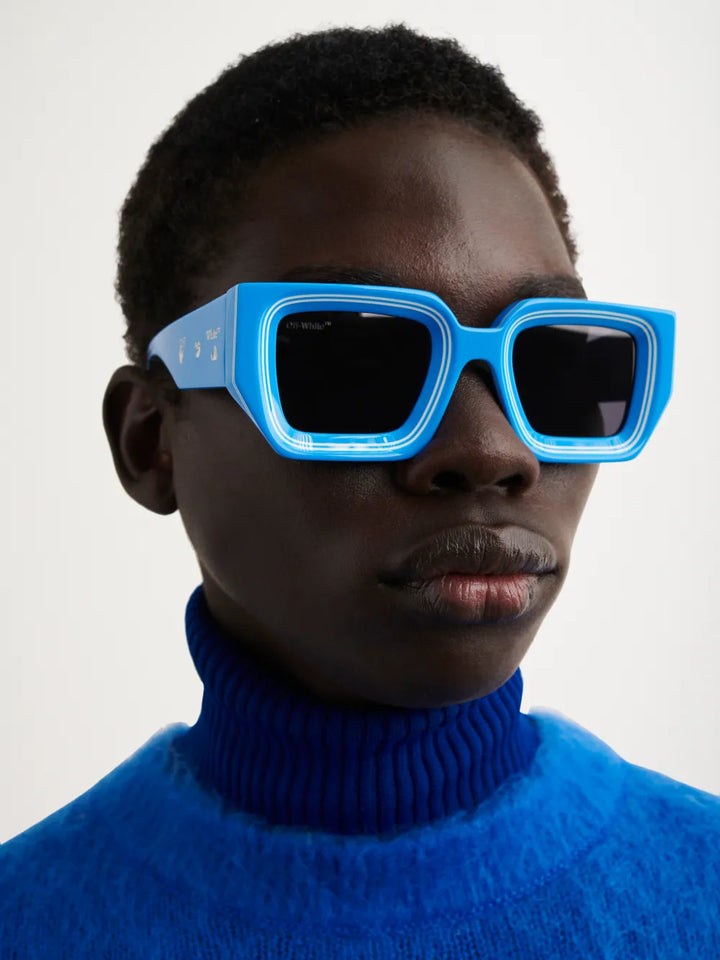 Blue Off-White Francisco sunglasses on face, bold square frames with dark lenses