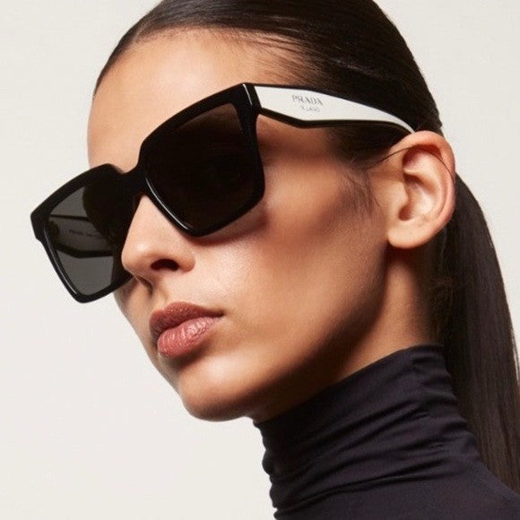 Woman wearing Prada oversized black sunglasses with dark tinted lenses