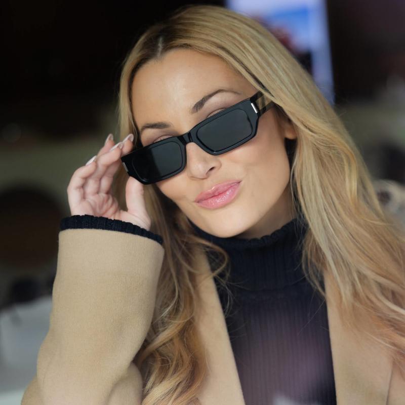 Saint Laurent SL660/F black rectangular sunglasses held at the temple, dark lenses