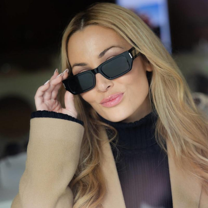 Saint Laurent SL660/F black rectangular sunglasses held at the temple, dark lenses