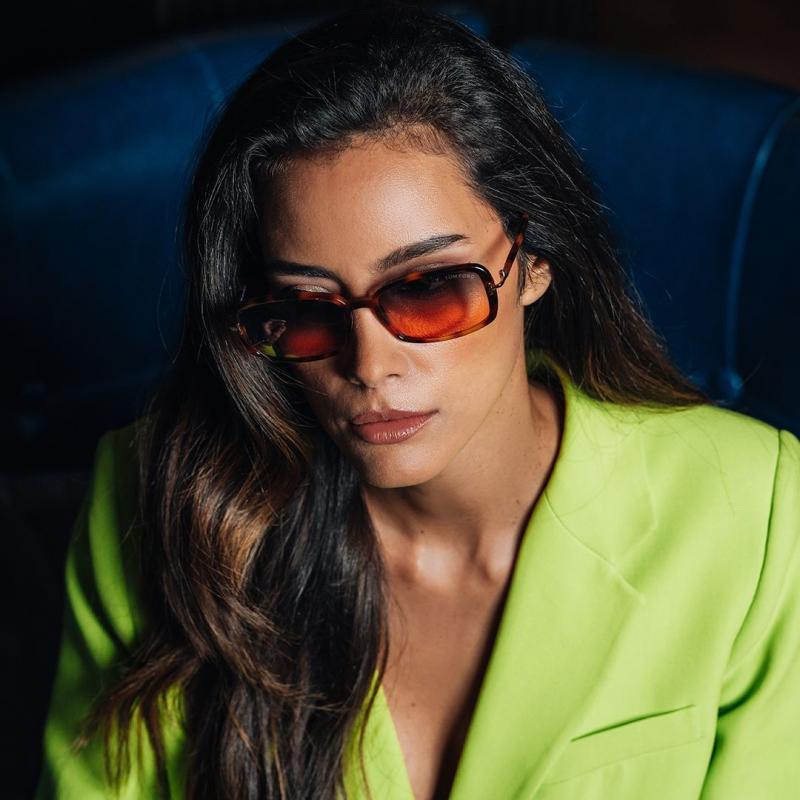 Sunglasses with red-tinted lenses and dark frames worn by model