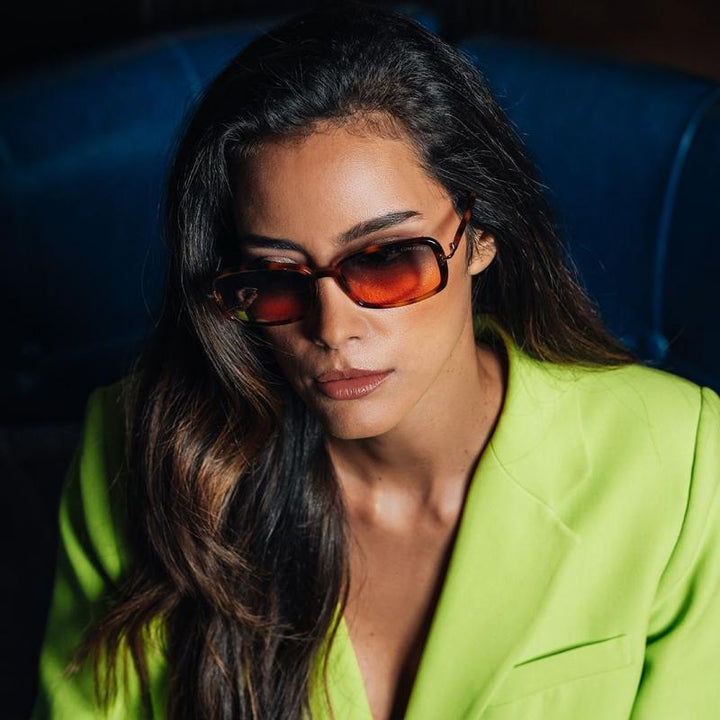 Sunglasses with red-tinted lenses and dark frames worn by model