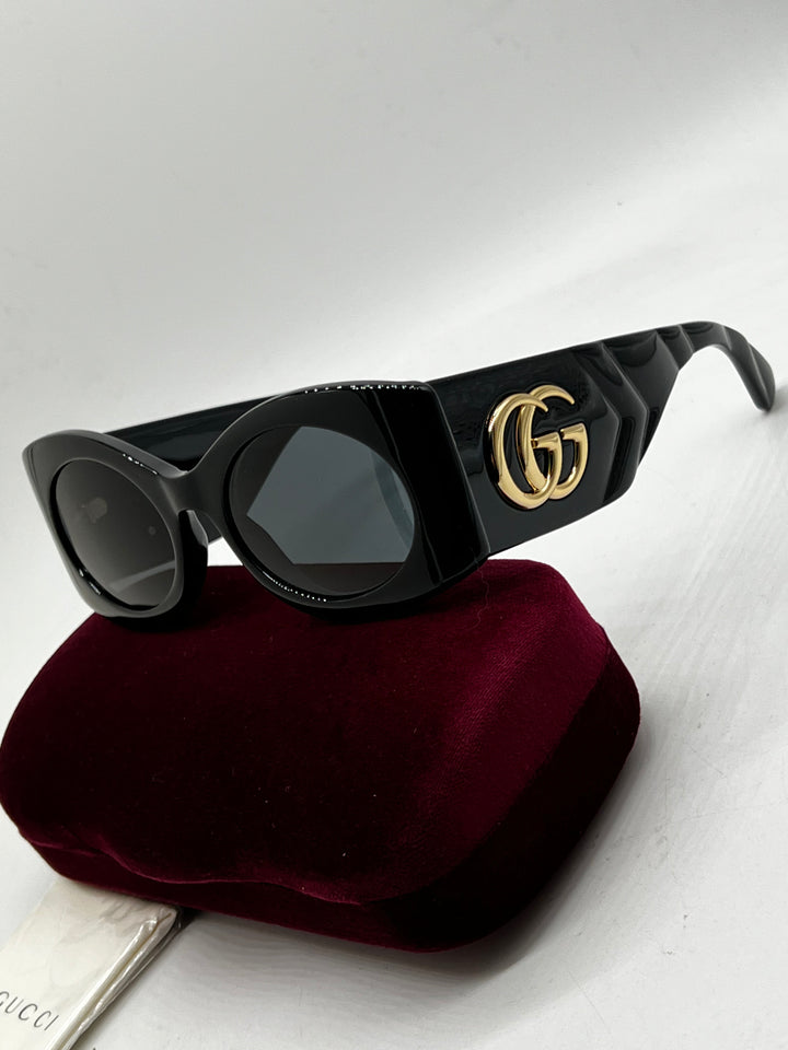 Black Gucci rectangular sunglasses with GG emblem on quilted temple, on case.