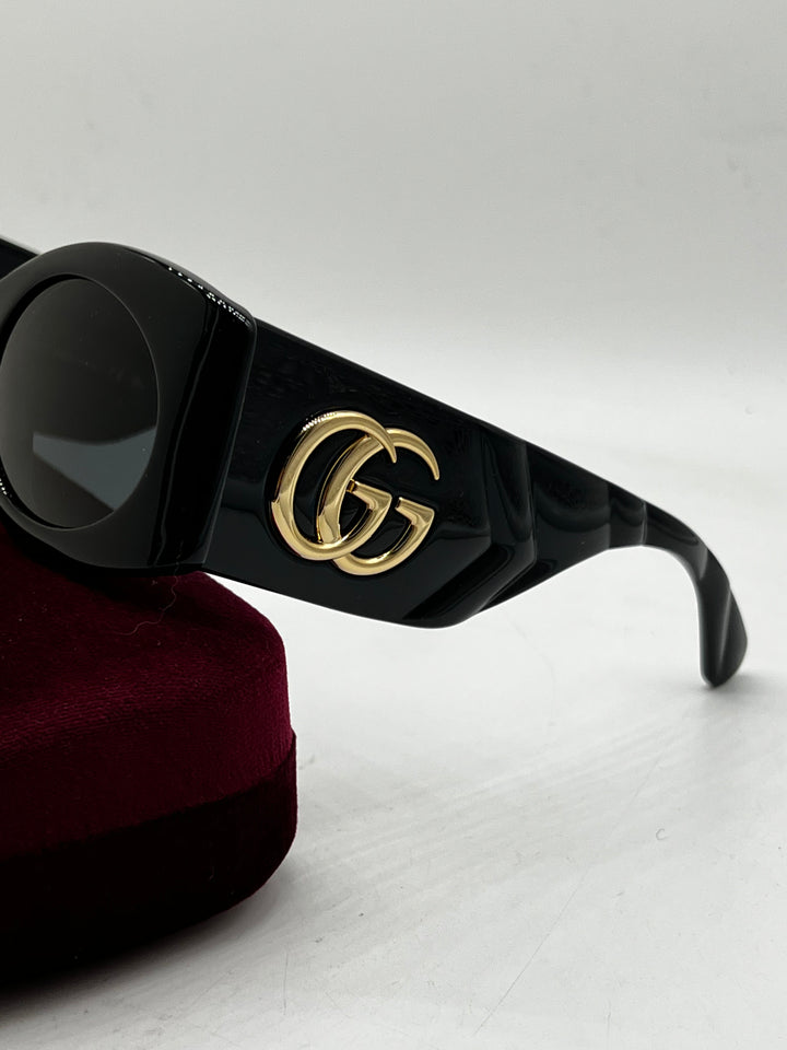 Black quilted temple sunglasses with gold GG emblem and dark lenses, side view.