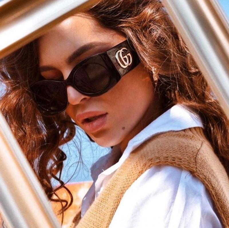 Black quilted Gucci sunglasses on model with GG logo temple and dark lenses.